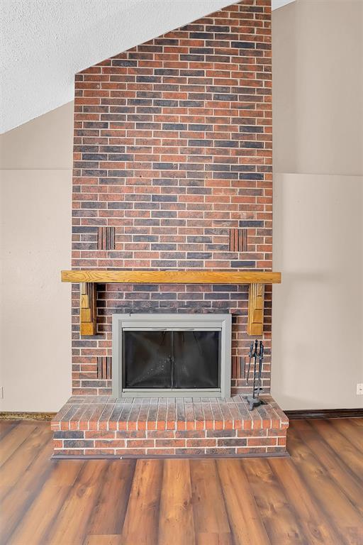 interior details with hardwood / wood-style floors, a textured ceiling, and a brick fireplace