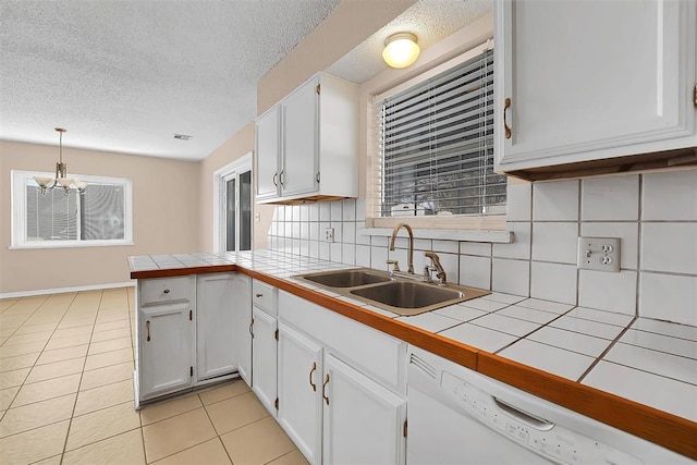 kitchen with dishwasher, tile countertops, white cabinets, and hanging light fixtures