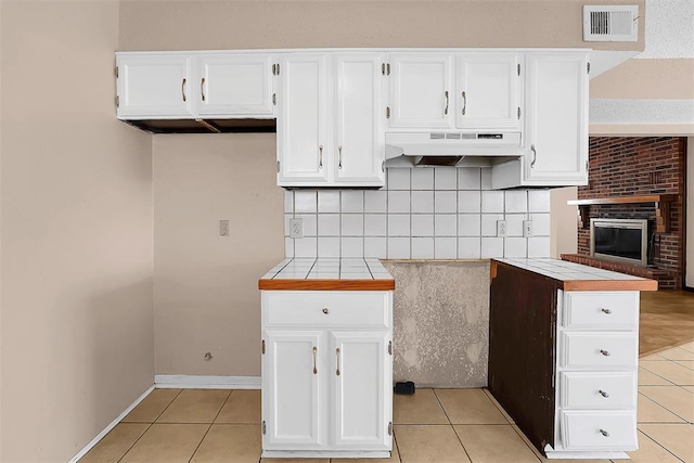 kitchen featuring tile counters, white cabinetry, and light tile patterned floors