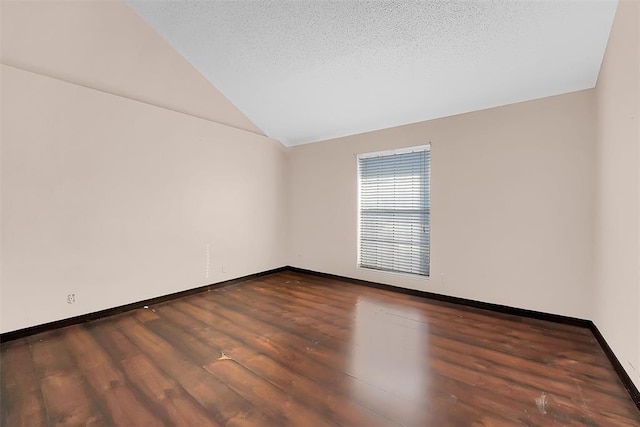 empty room with a textured ceiling, dark hardwood / wood-style floors, and lofted ceiling