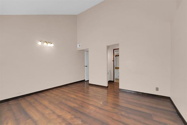 spare room featuring high vaulted ceiling and dark hardwood / wood-style floors