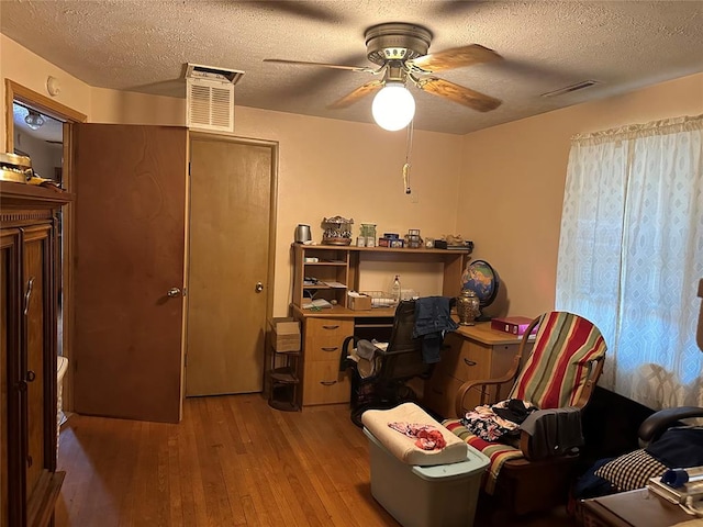 office area with ceiling fan, light hardwood / wood-style floors, and a textured ceiling