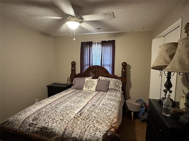 bedroom with ceiling fan, wood-type flooring, and a textured ceiling