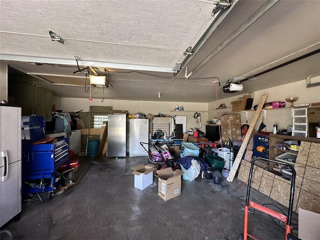 garage featuring stainless steel fridge, white fridge, and a garage door opener