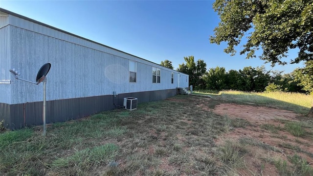 view of side of home with a yard and central AC