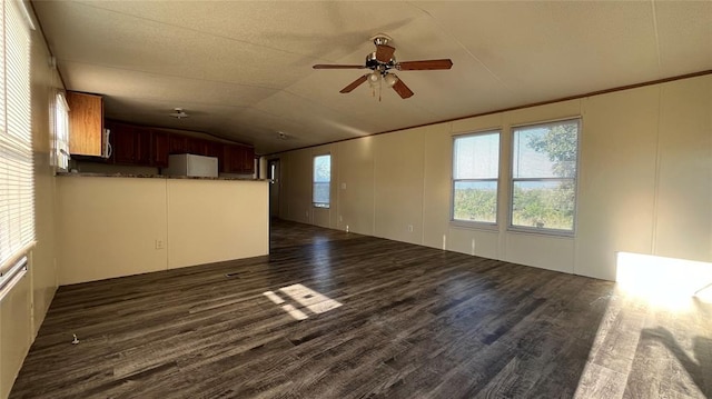 unfurnished living room with a textured ceiling, ceiling fan, dark wood-type flooring, and lofted ceiling