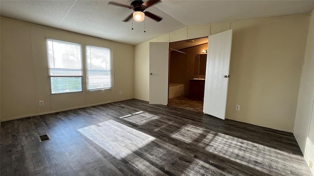 unfurnished bedroom with a textured ceiling, ceiling fan, lofted ceiling, and dark wood-type flooring