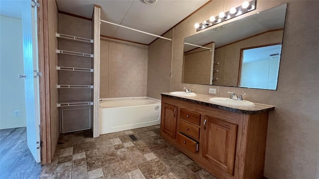 bathroom with a bathing tub, vanity, ornamental molding, and vaulted ceiling