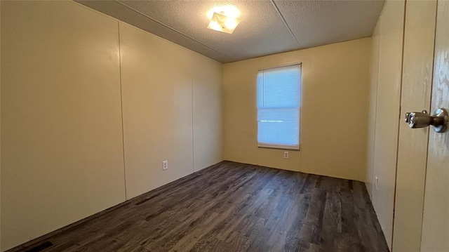 unfurnished room featuring a textured ceiling and dark wood-type flooring