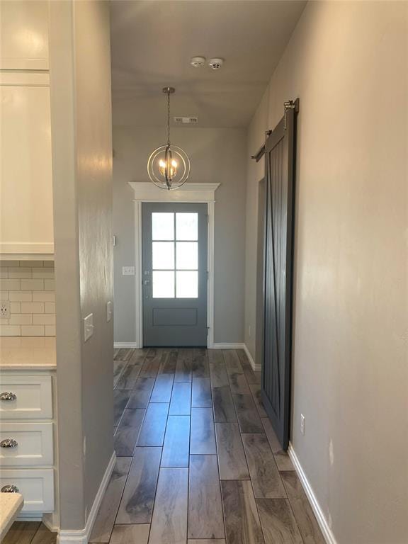 doorway with dark hardwood / wood-style floors and a notable chandelier