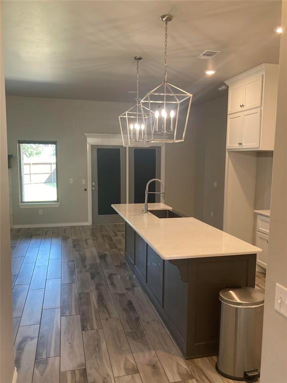 kitchen featuring white cabinets, dark hardwood / wood-style flooring, decorative light fixtures, and sink