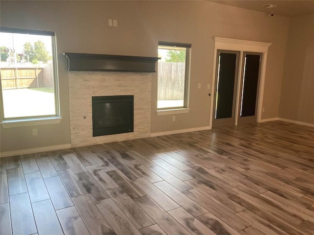 unfurnished living room featuring a tile fireplace and wood-type flooring