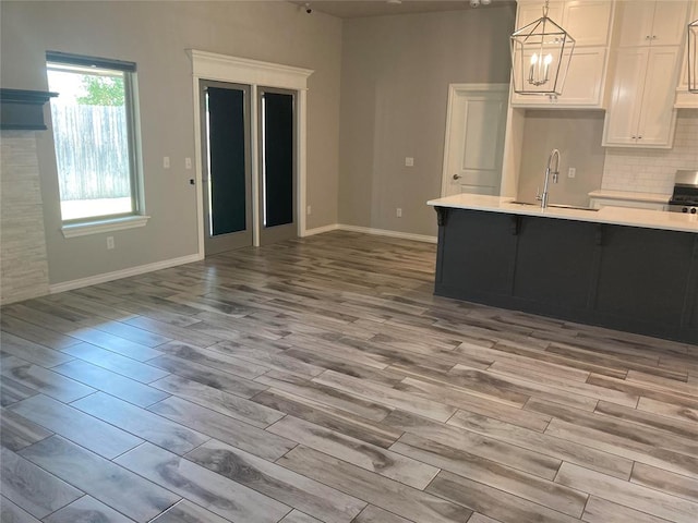 kitchen with pendant lighting, light hardwood / wood-style floors, white cabinetry, and sink