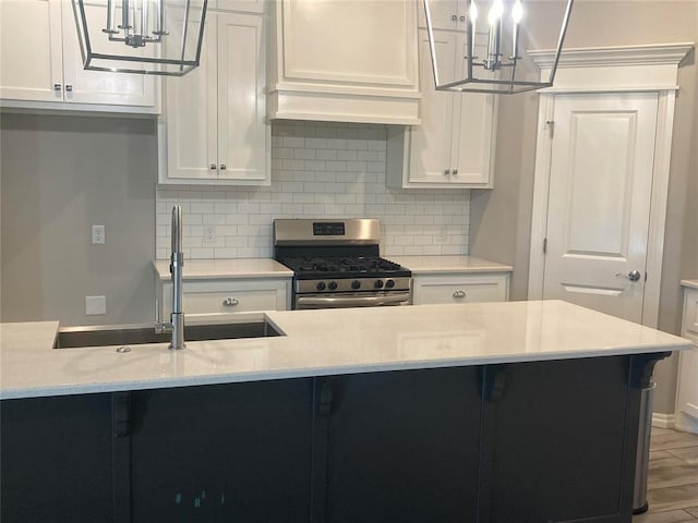 kitchen featuring light stone countertops, stainless steel gas stove, backsplash, pendant lighting, and hardwood / wood-style flooring