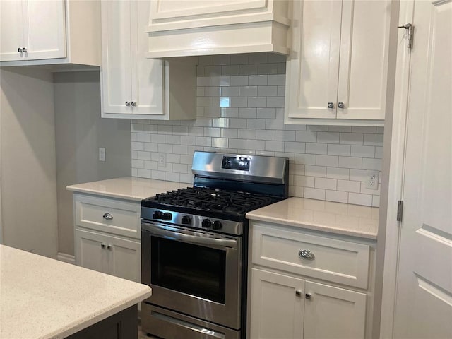 kitchen featuring decorative backsplash, white cabinetry, custom exhaust hood, and stainless steel range with gas stovetop