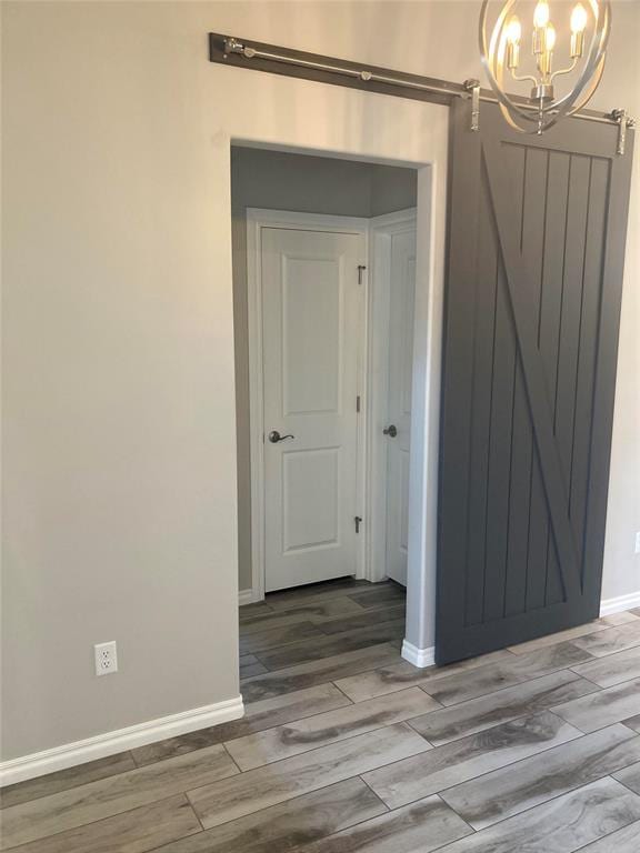 interior space featuring hardwood / wood-style floors, a barn door, and a chandelier