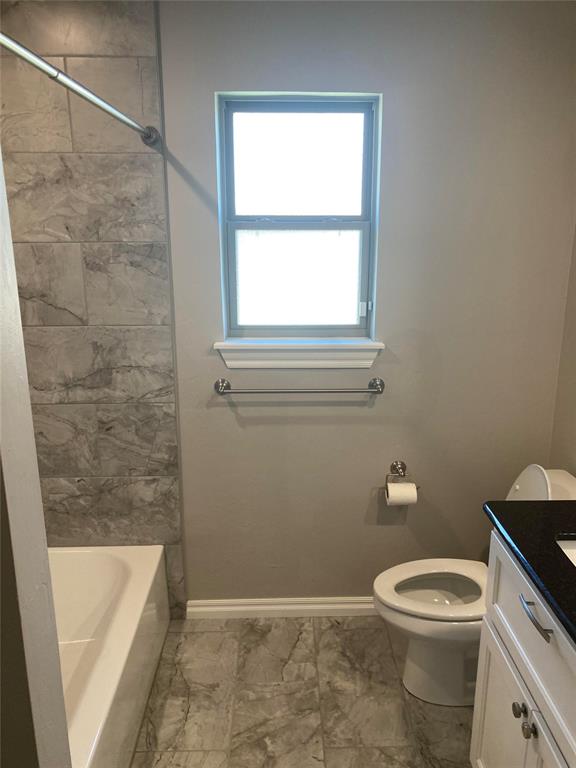 full bathroom with vanity, tiled shower / bath combo, and toilet