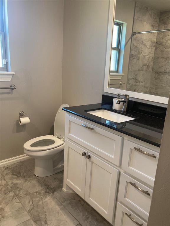 bathroom with tiled shower, vanity, and toilet