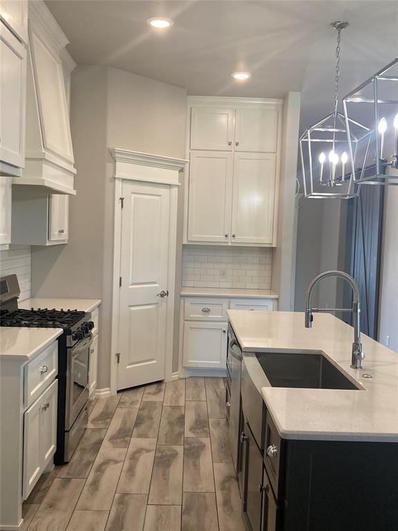 kitchen featuring white cabinets, decorative light fixtures, stainless steel appliances, and light hardwood / wood-style flooring