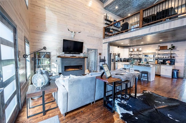 living room with dark hardwood / wood-style floors, a towering ceiling, and wooden walls