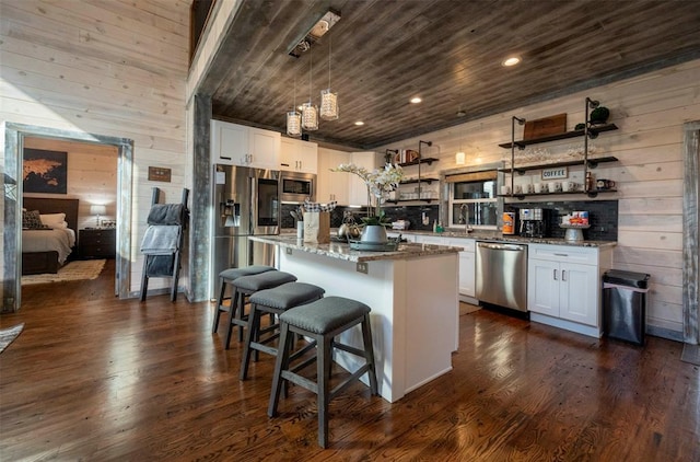 kitchen with white cabinets, a kitchen island, dark wood-type flooring, and appliances with stainless steel finishes