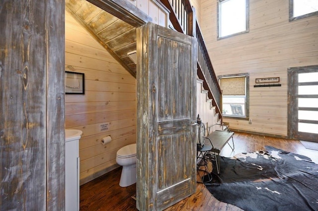 bathroom with wooden walls, hardwood / wood-style floors, lofted ceiling, and toilet