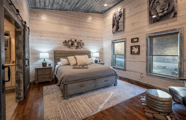 bedroom featuring wood walls, dark hardwood / wood-style floors, a barn door, and lofted ceiling