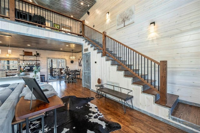 stairway with wooden walls, a high ceiling, and hardwood / wood-style flooring