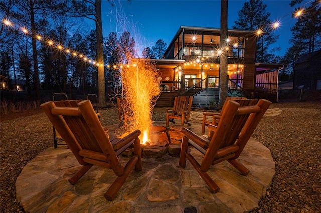 patio at night featuring a fire pit and a balcony