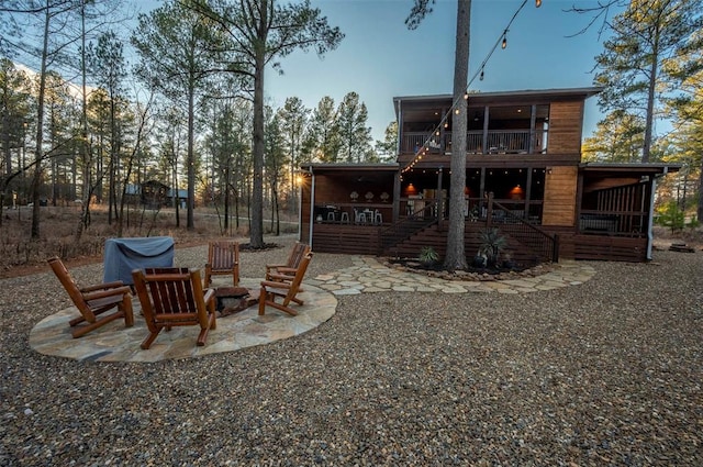 back house at dusk featuring a patio area and an outdoor fire pit