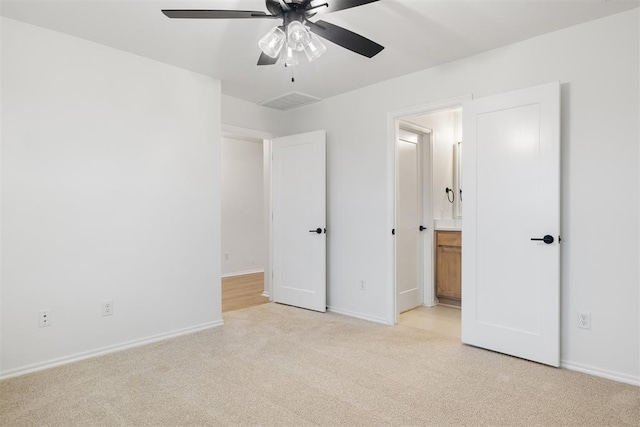 unfurnished bedroom featuring ensuite bathroom, ceiling fan, and light carpet