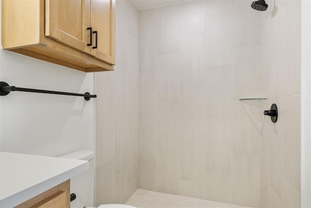 bathroom with vanity, toilet, and a tile shower