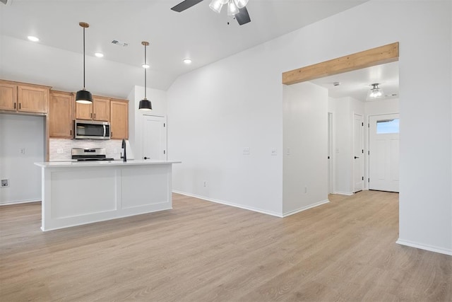 kitchen featuring appliances with stainless steel finishes, a kitchen island with sink, ceiling fan, light hardwood / wood-style flooring, and hanging light fixtures