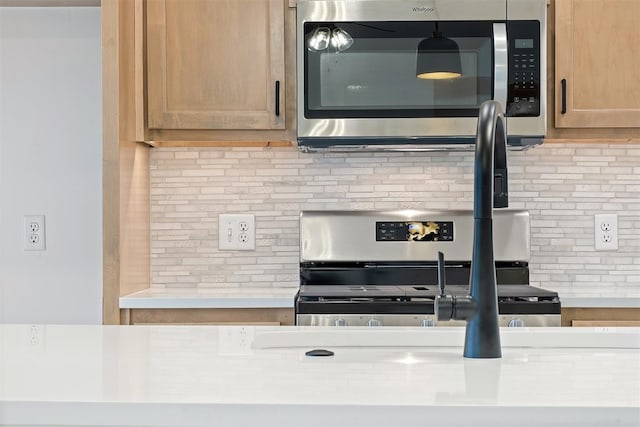 kitchen with decorative backsplash, light brown cabinets, and stainless steel appliances