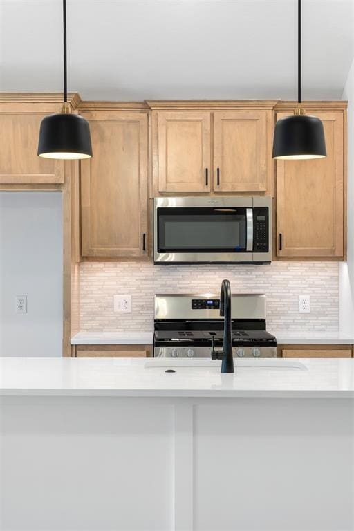 kitchen featuring decorative backsplash, sink, stainless steel appliances, and decorative light fixtures