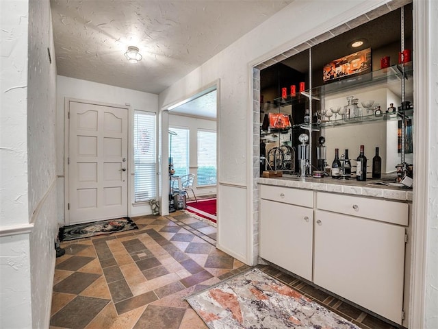 foyer entrance with a textured ceiling and bar