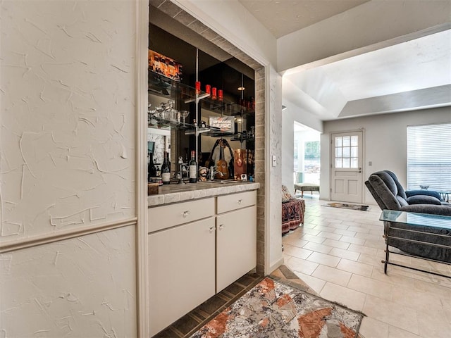 bar with tile patterned floors and white cabinetry