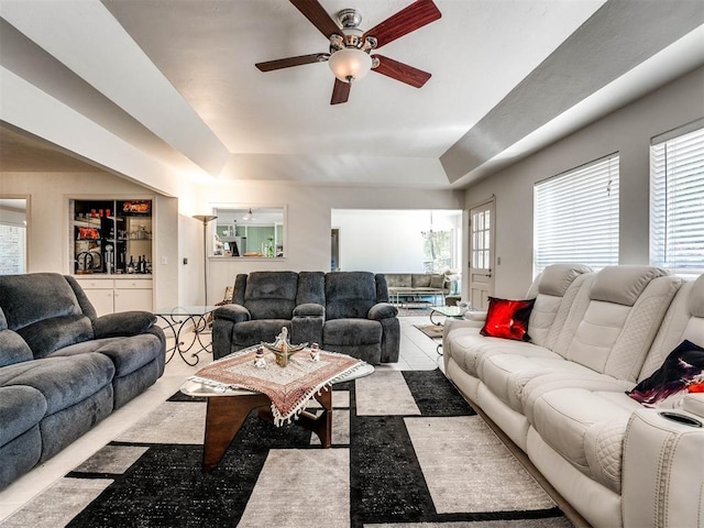 living room with a raised ceiling and ceiling fan