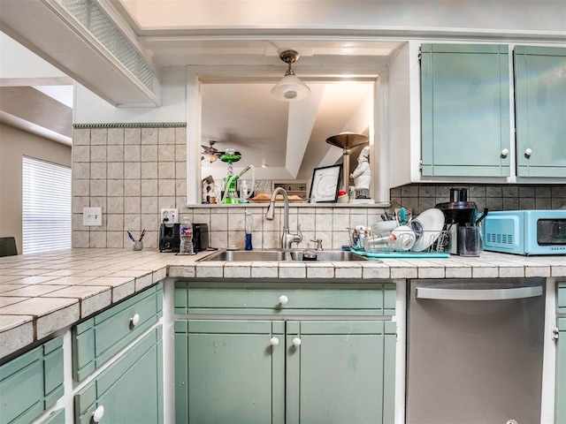 kitchen with tile counters, sink, pendant lighting, and stainless steel dishwasher