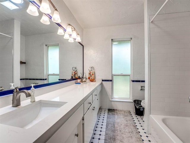 bathroom with tile patterned flooring, vanity, tile walls, and tiled shower / bath combo