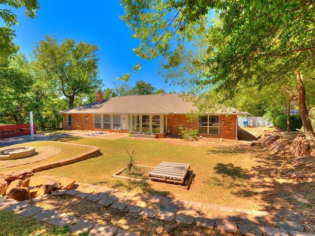 back of house featuring a yard and an outdoor fire pit