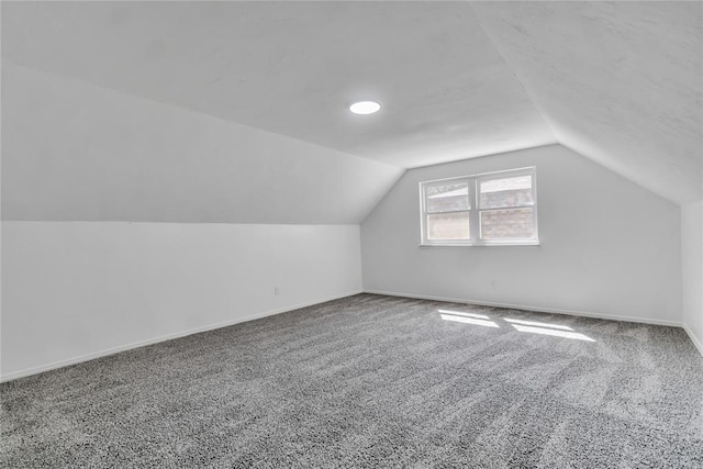 bonus room with vaulted ceiling and carpet floors