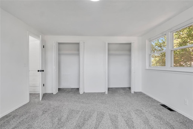 unfurnished bedroom with light carpet and two closets