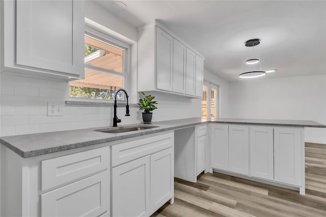 kitchen featuring white cabinetry, kitchen peninsula, sink, and hanging light fixtures