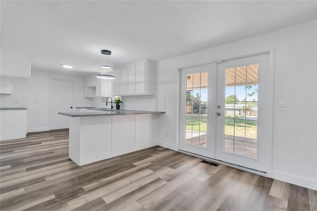 kitchen with white cabinetry, hanging light fixtures, kitchen peninsula, and french doors