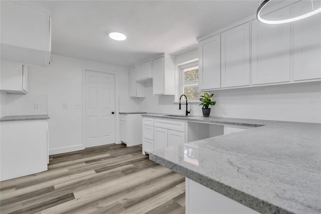 kitchen with white cabinetry, light hardwood / wood-style floors, sink, and tasteful backsplash