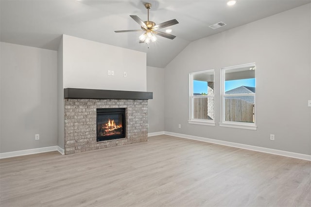 unfurnished living room featuring ceiling fan, a fireplace, light hardwood / wood-style floors, and vaulted ceiling