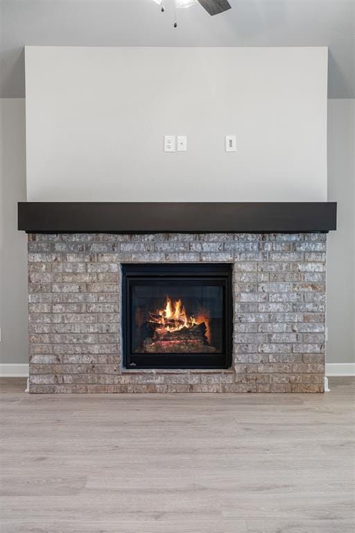 room details featuring hardwood / wood-style flooring, a brick fireplace, and ceiling fan