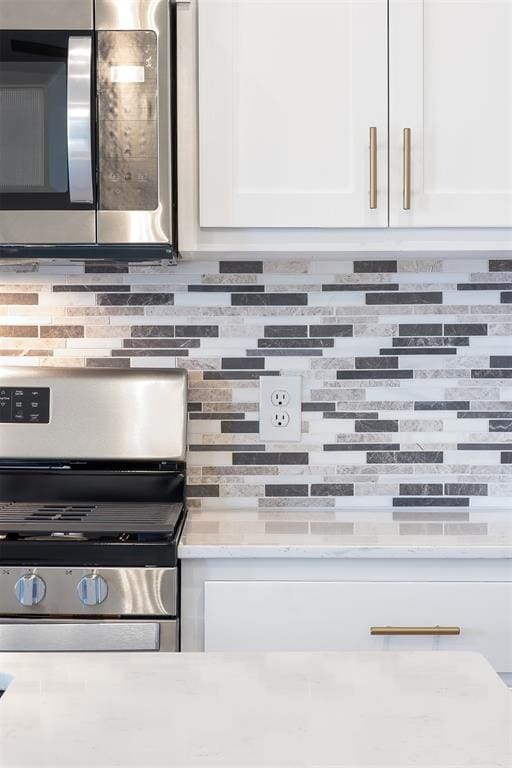 details featuring backsplash, white cabinetry, and stainless steel appliances