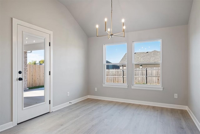 unfurnished dining area featuring light hardwood / wood-style flooring, a healthy amount of sunlight, vaulted ceiling, and a notable chandelier